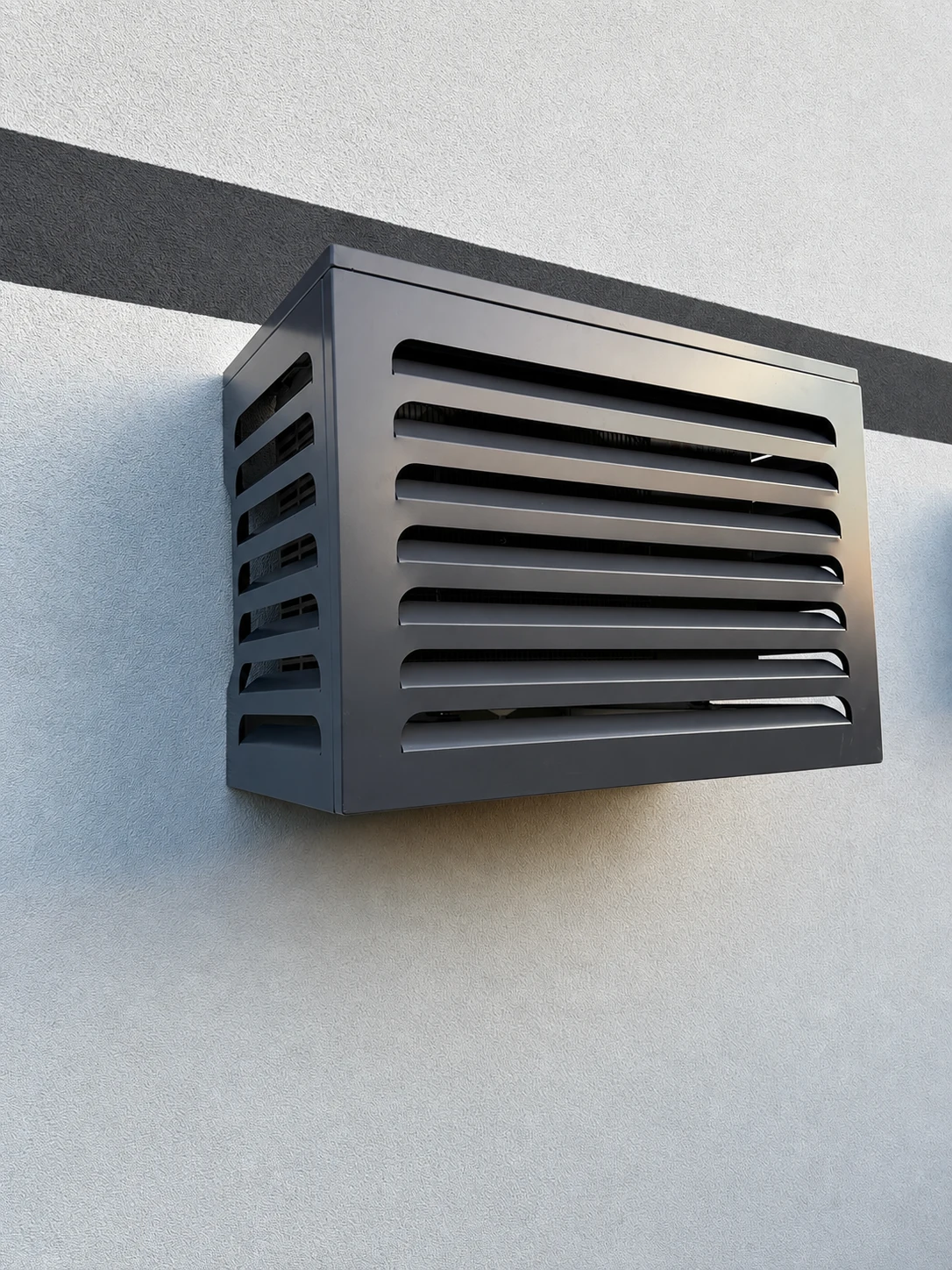 An anthracite louvered Matro cover concealing an outdoor air-conditioning unit on a rendered facade